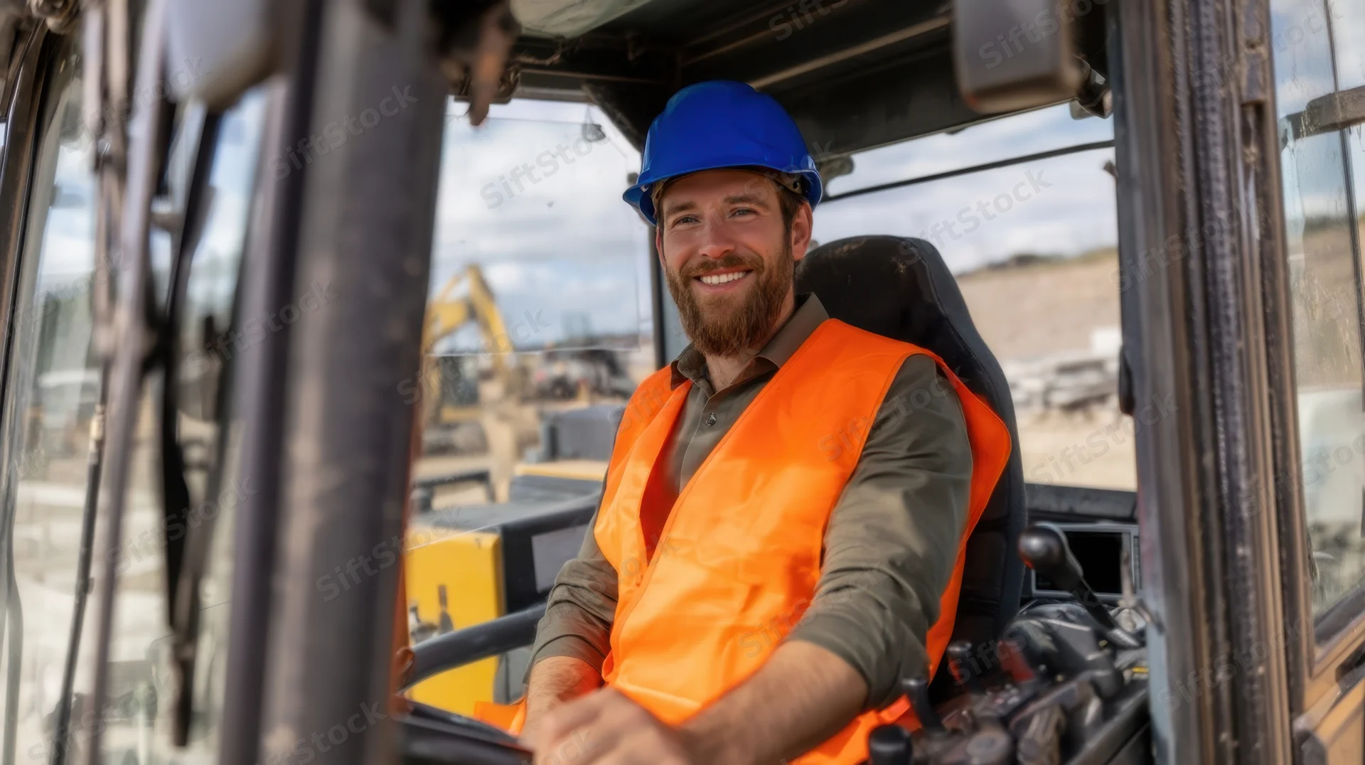 Smiling construction worker in safety gear seated inside heavy machinery cab at outdoor site