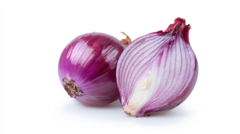 Two red onions, one whole and one halved, on a white background