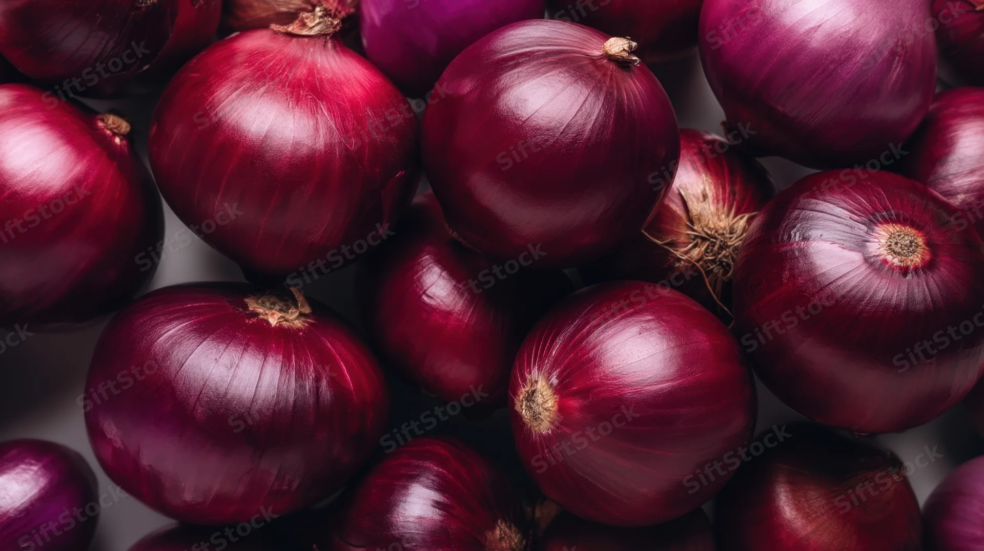Closeup of red onions piled together on a neutral surface