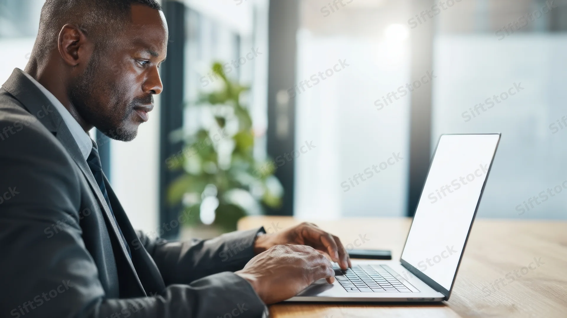 Man in suit typing on laptop at office desk