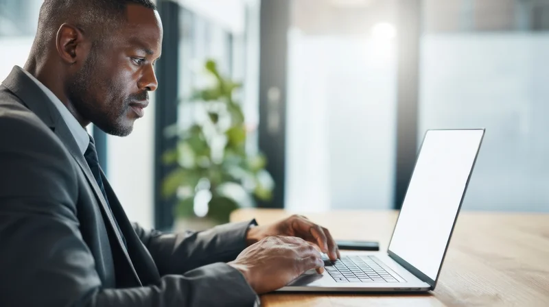 Man in suit typing on laptop at office desk