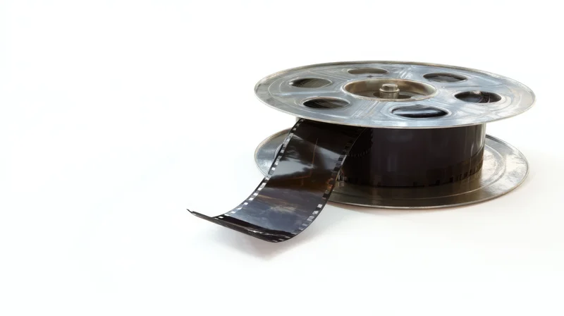 Metallic film reel with unspooled strip on white background