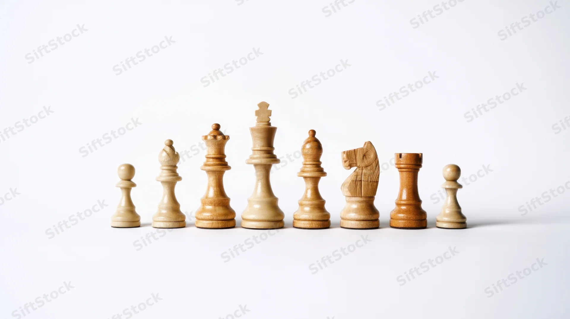 Wooden chess pieces arranged in a row on a white surface