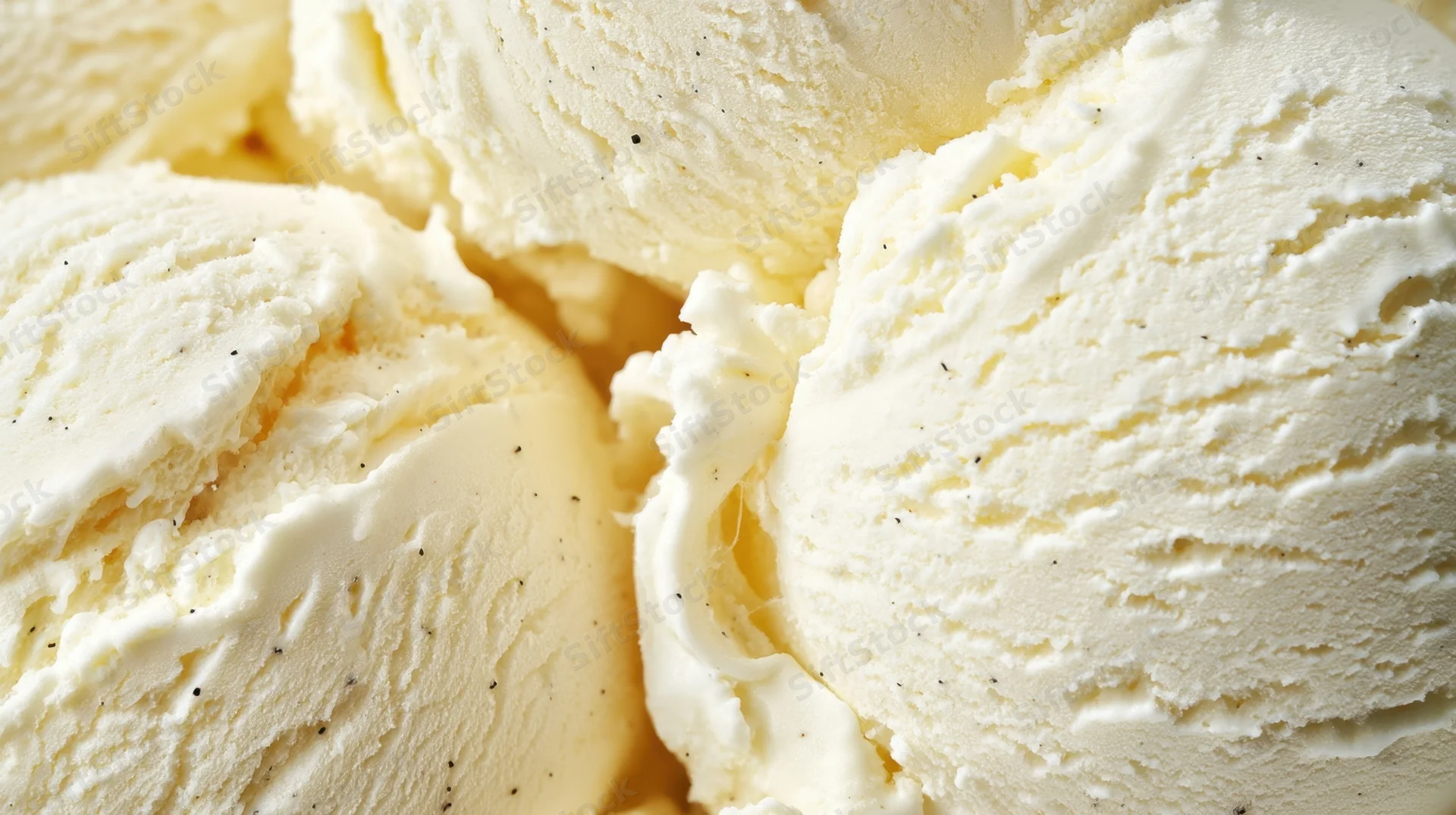 Closeup of smooth vanilla ice cream scoops with visible texture and specks