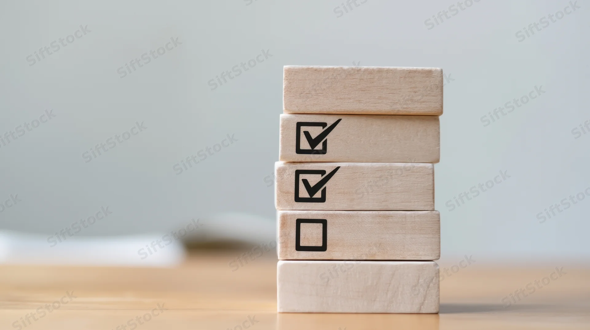 Stack of wooden blocks with checkmarks arranged vertically on a desk
