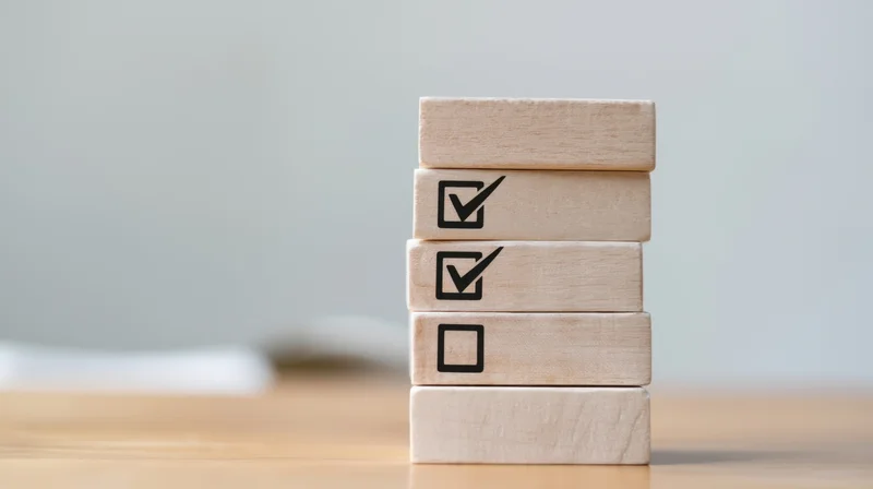 Stack of wooden blocks with checkmarks arranged vertically on a desk