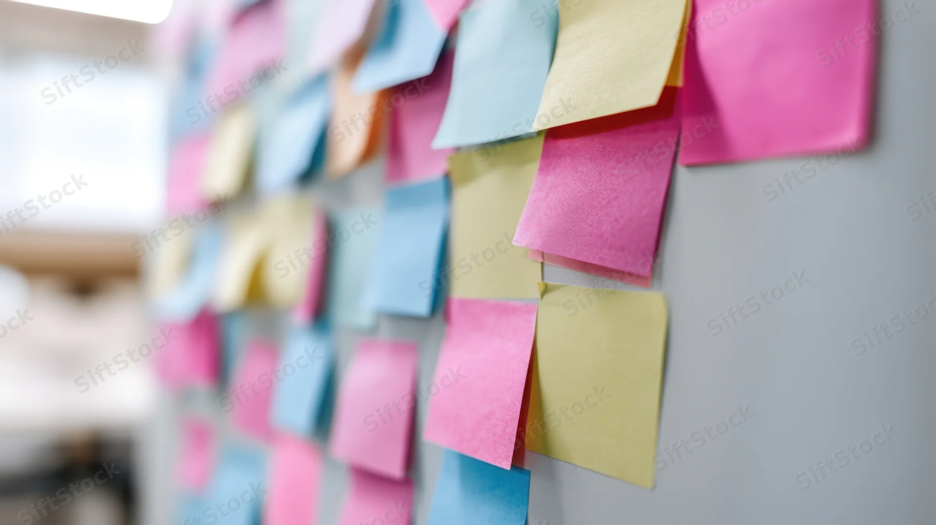 Colorful sticky notes arranged on a gray office wall for brainstorming and project planning