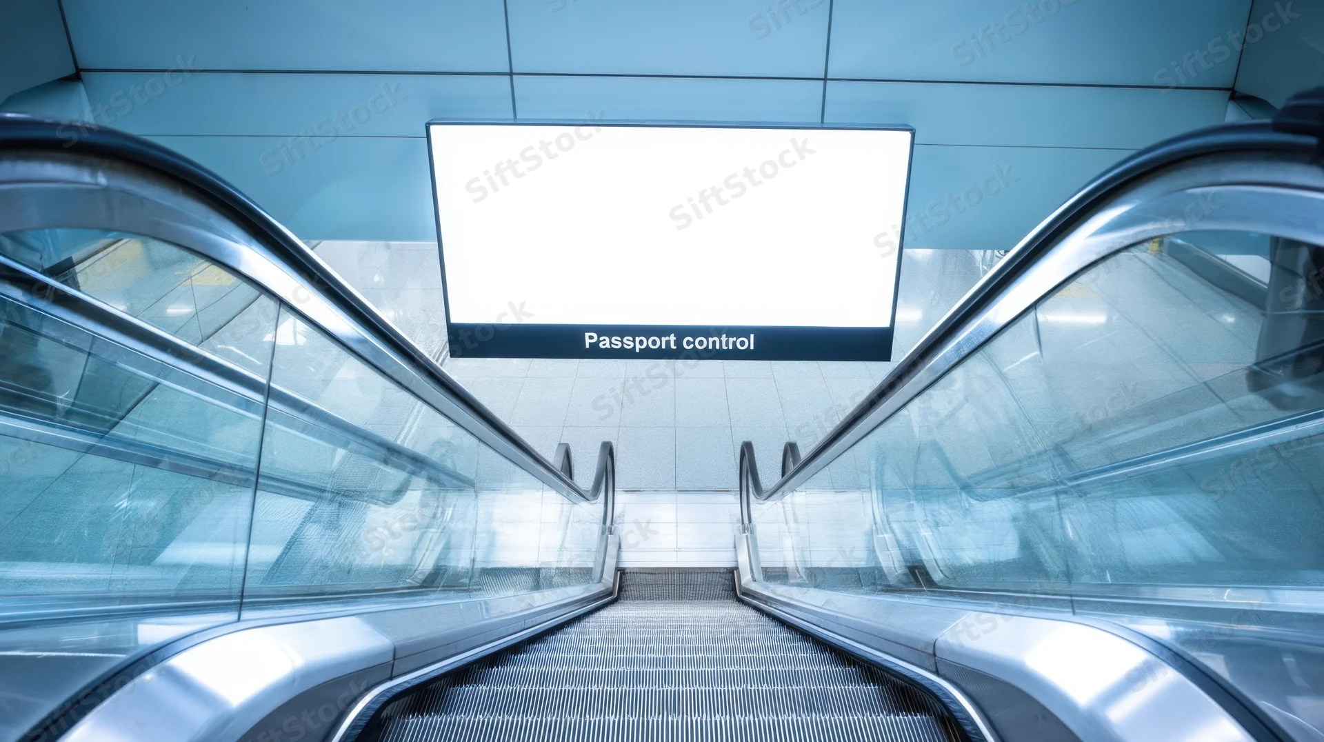 Escalator leading upward toward passport control sign in airport terminal