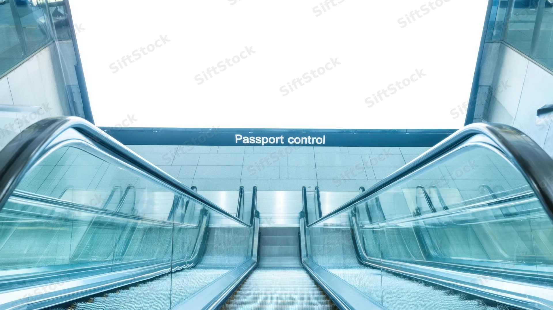 Escalators leading to passport control sign in airport terminal