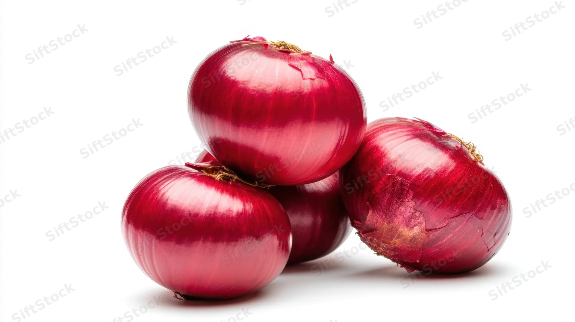 Four red onions stacked on a white surface