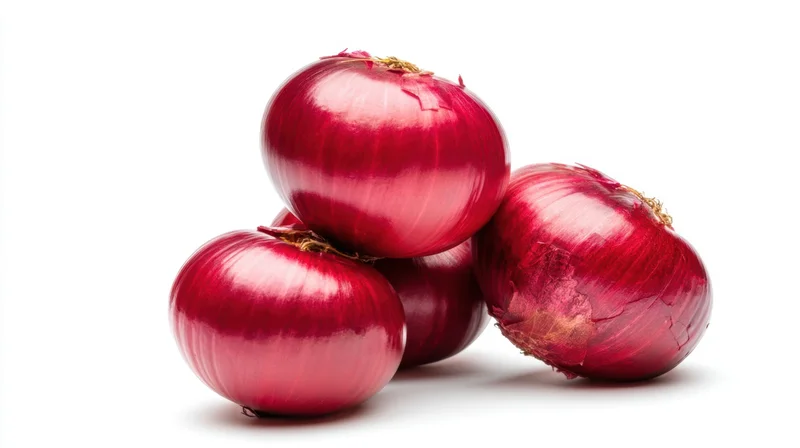 Four red onions stacked on a white surface