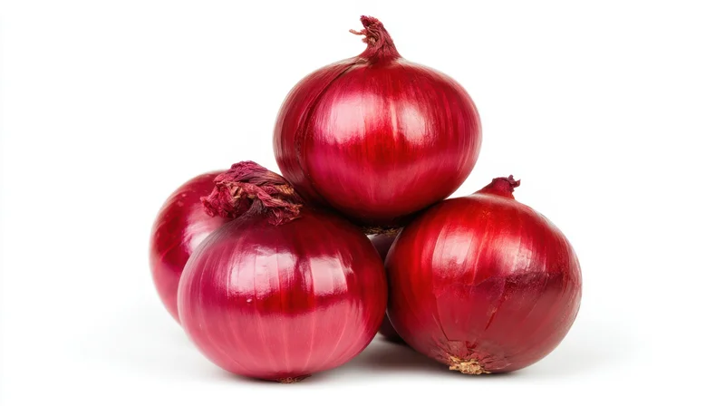 Four red onions stacked in a pile on a white background