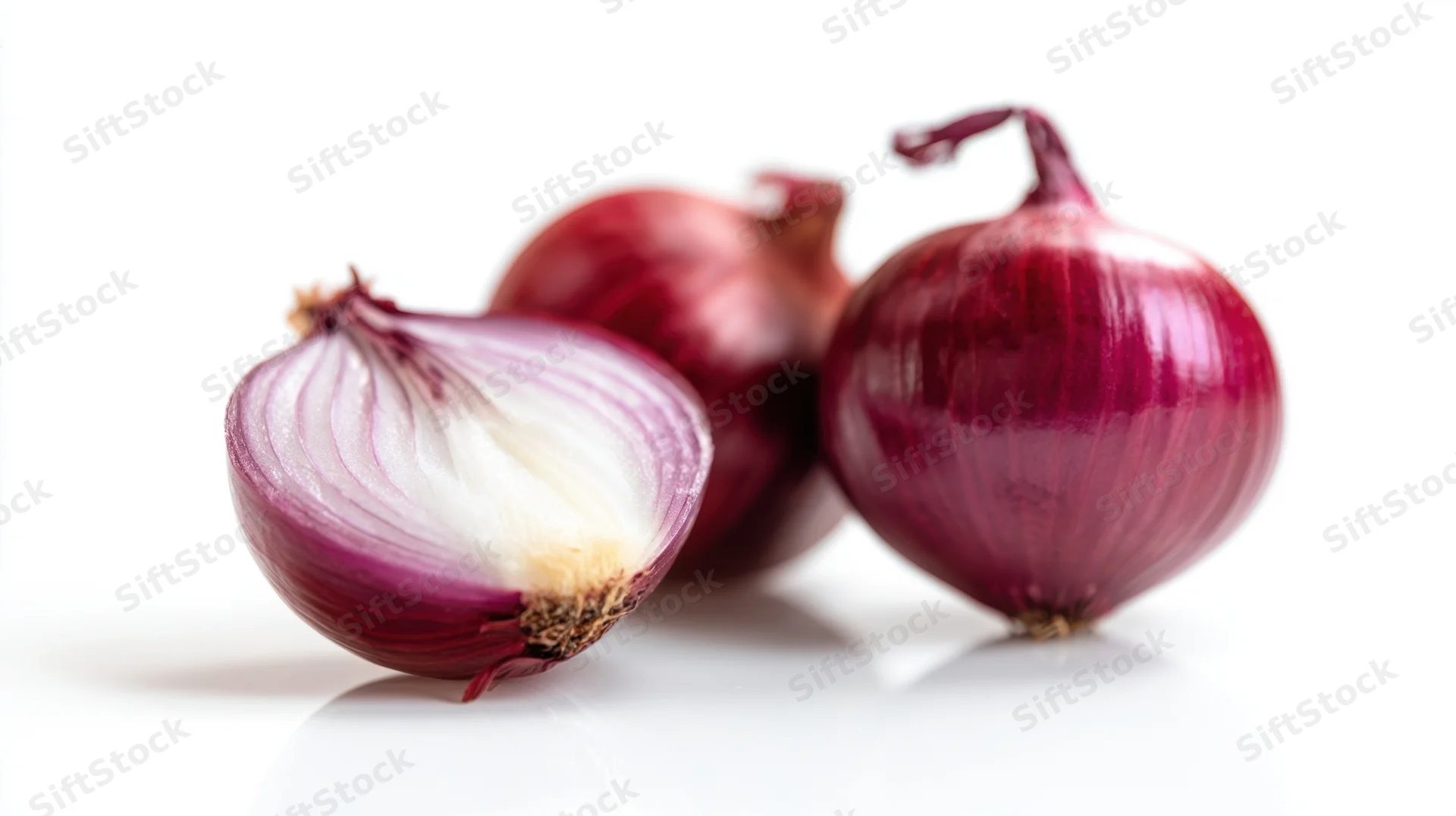 Three fresh red onions, one halved, on a white surface
