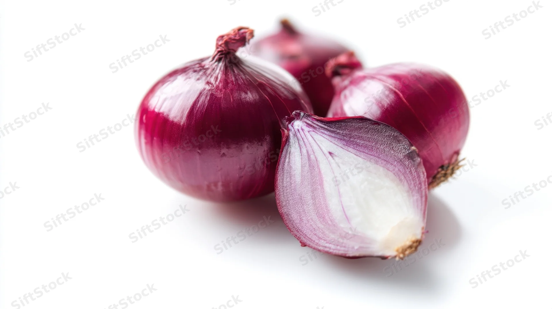 Fresh red onions with one halved on white background