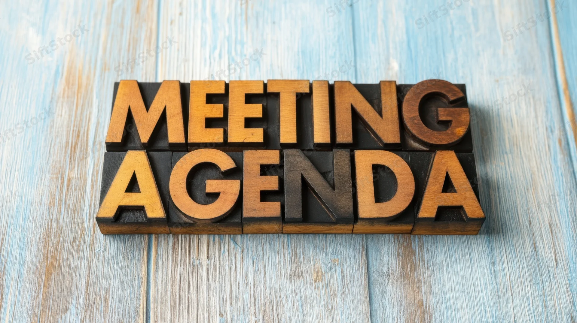 Wooden letters spelling meeting agenda arranged on a blue wooden surface