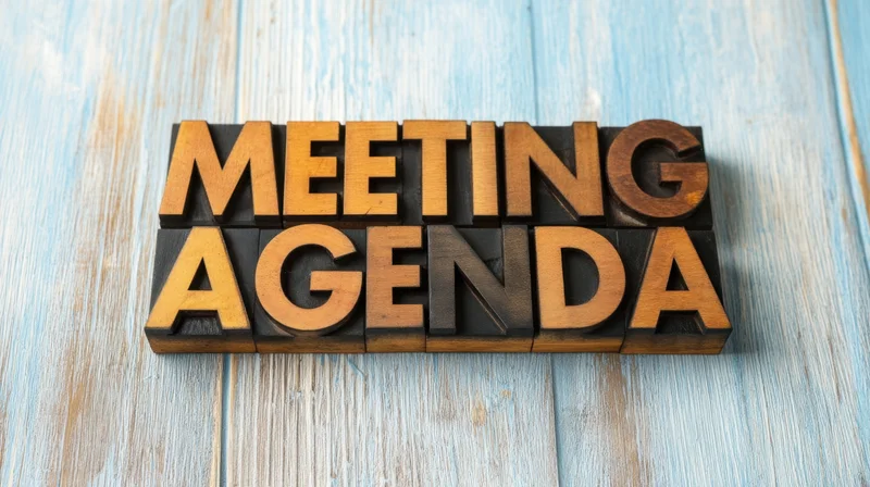 Wooden letters spelling meeting agenda arranged on a blue wooden surface