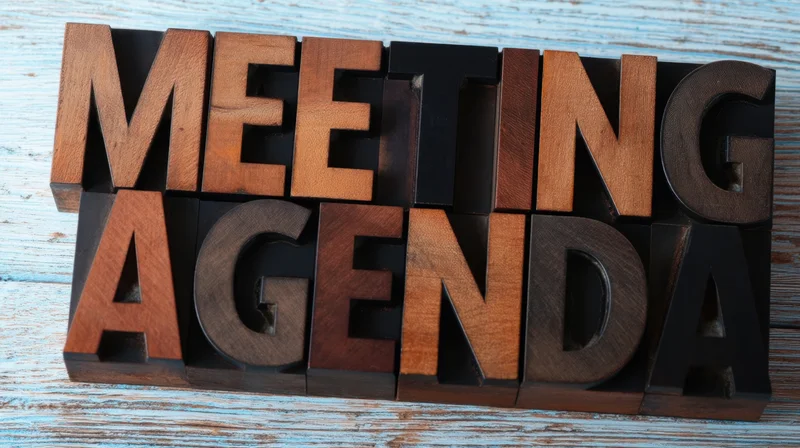 Wooden block letters spelling meeting agenda on a weathered blue wooden surface