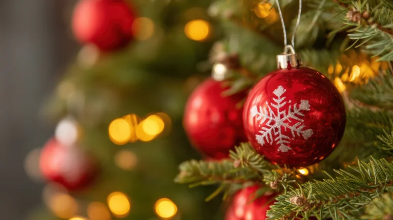Red snowflake ornament hanging on a decorated christmas tree with warm glowing lights