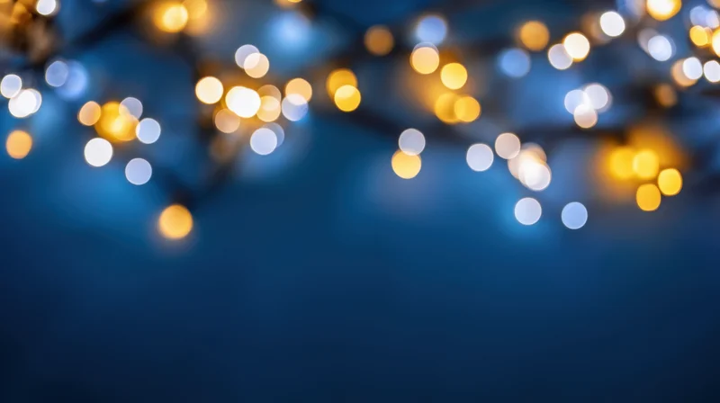 Blurred string lights glowing softly against a dark blue background with bokeh effect
