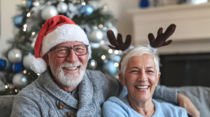 Senior couple smiling together on sofa with christmas tree and decorations behind them