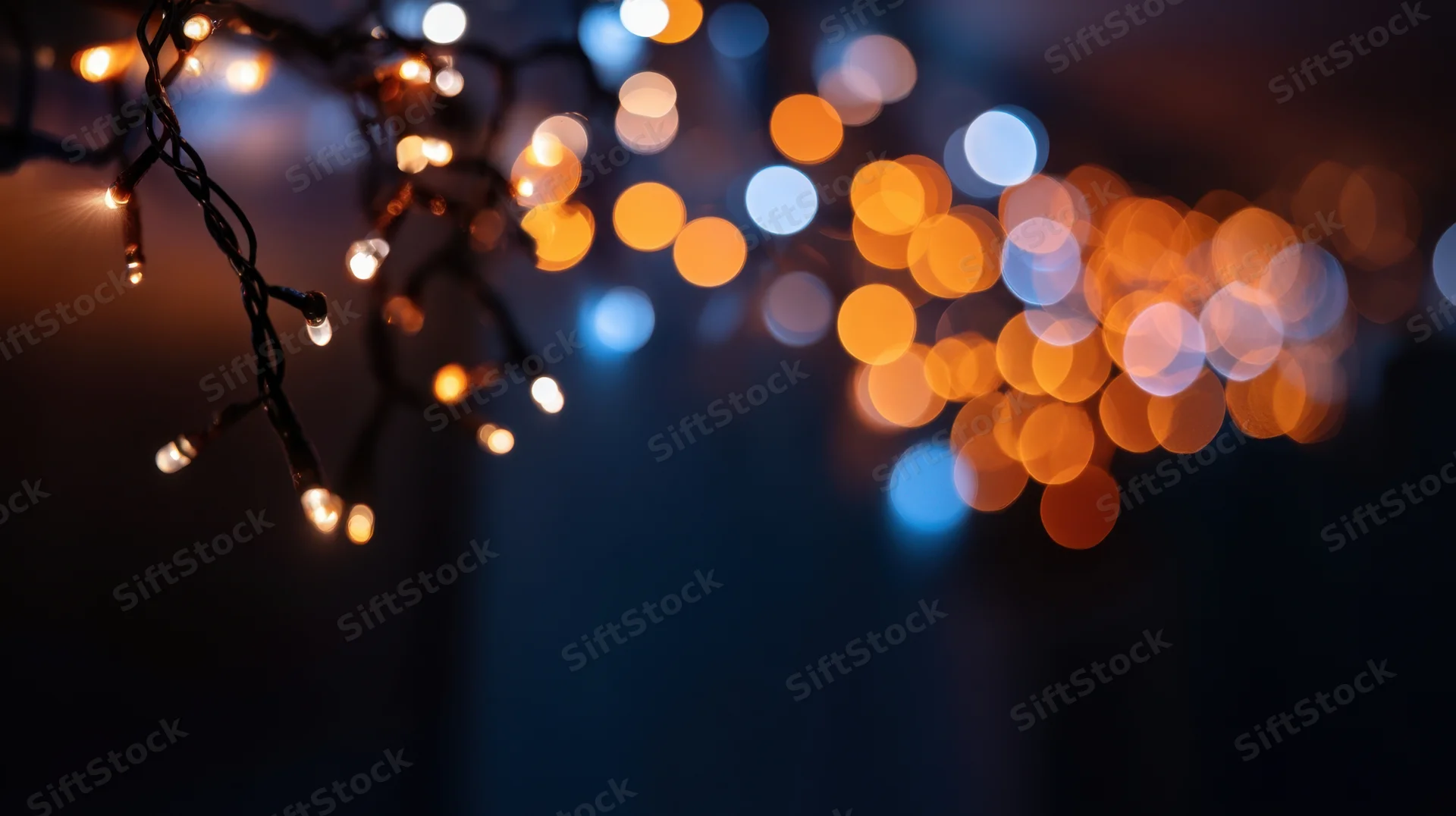 Close-up of glowing christmas fairy lights with bokeh effect against dark background