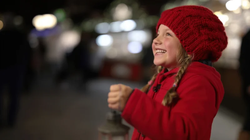 Young girl smiling while holding a lantern outdoors at night during a festive holiday event