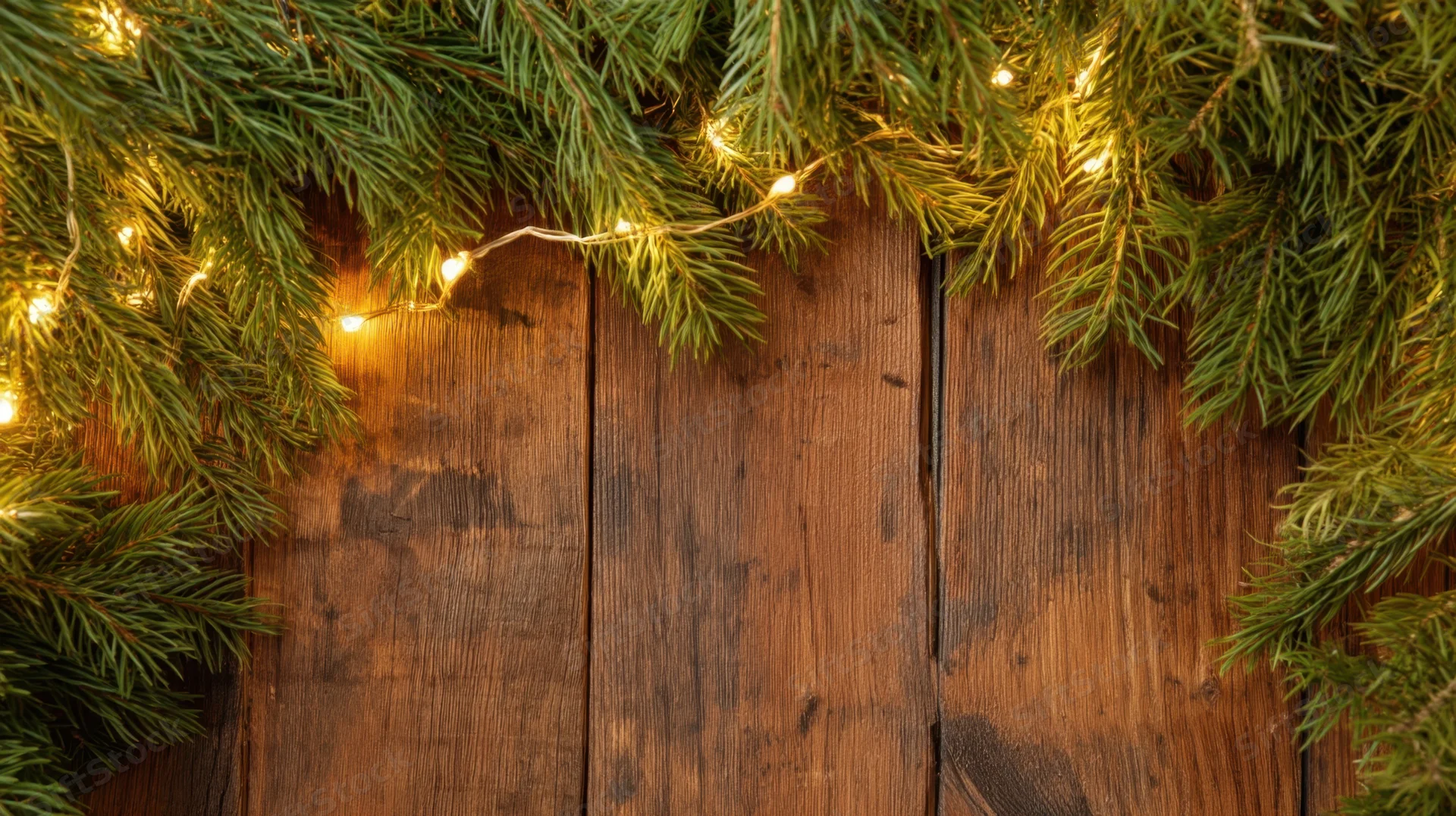 Pine branches with string lights framing a rustic wooden table surface