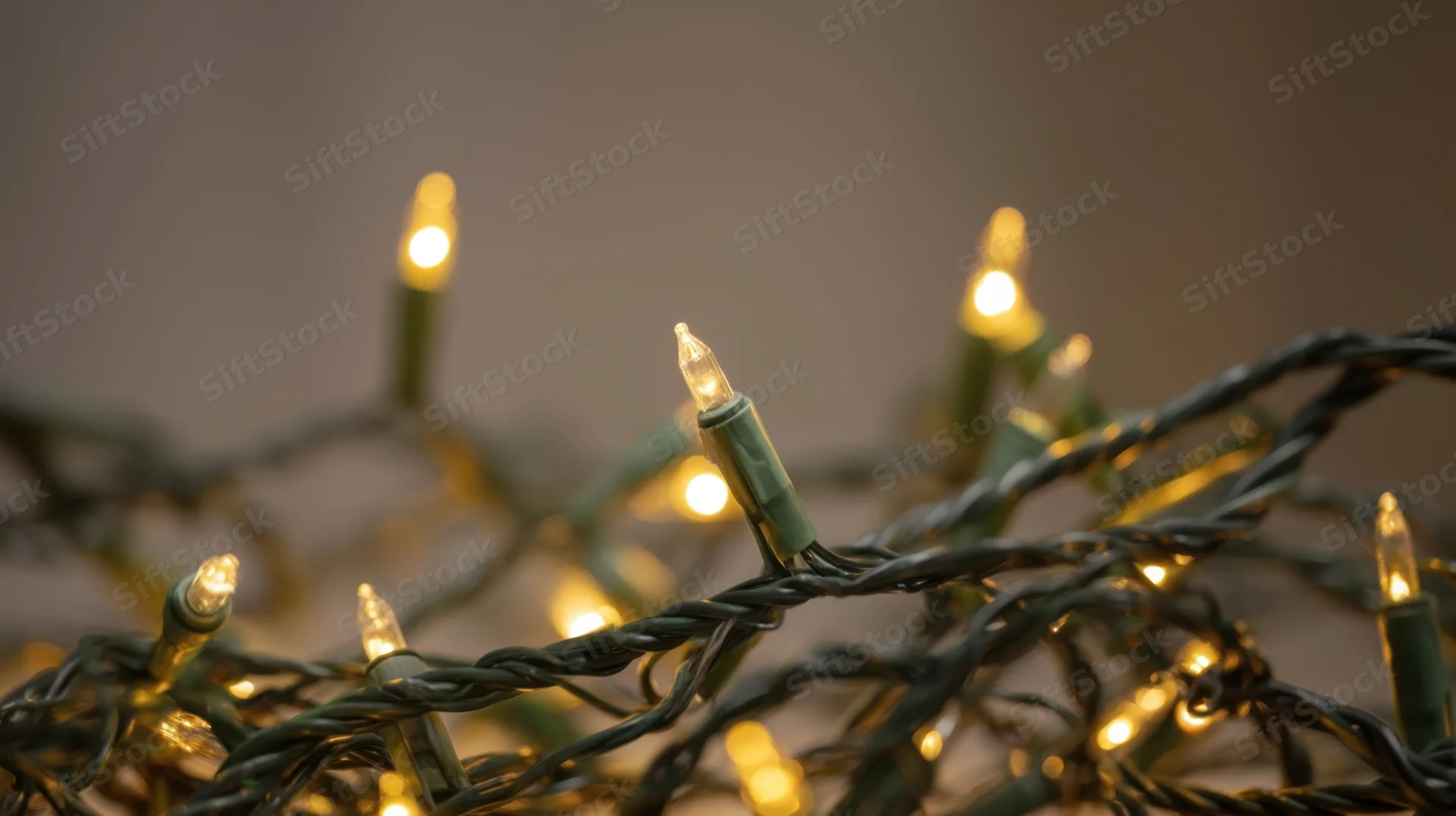 Tangled string of warm yellow holiday lights glowing softly in closeup view