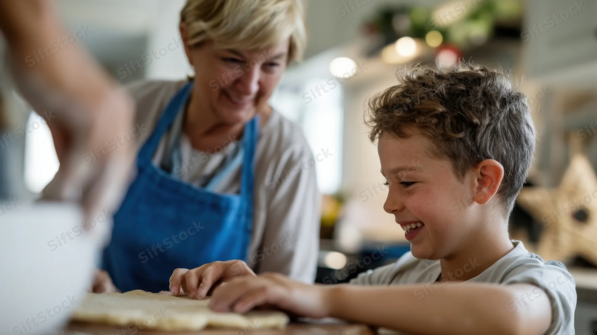 Grandmother and boy smiling while baking dough together in a kitchen