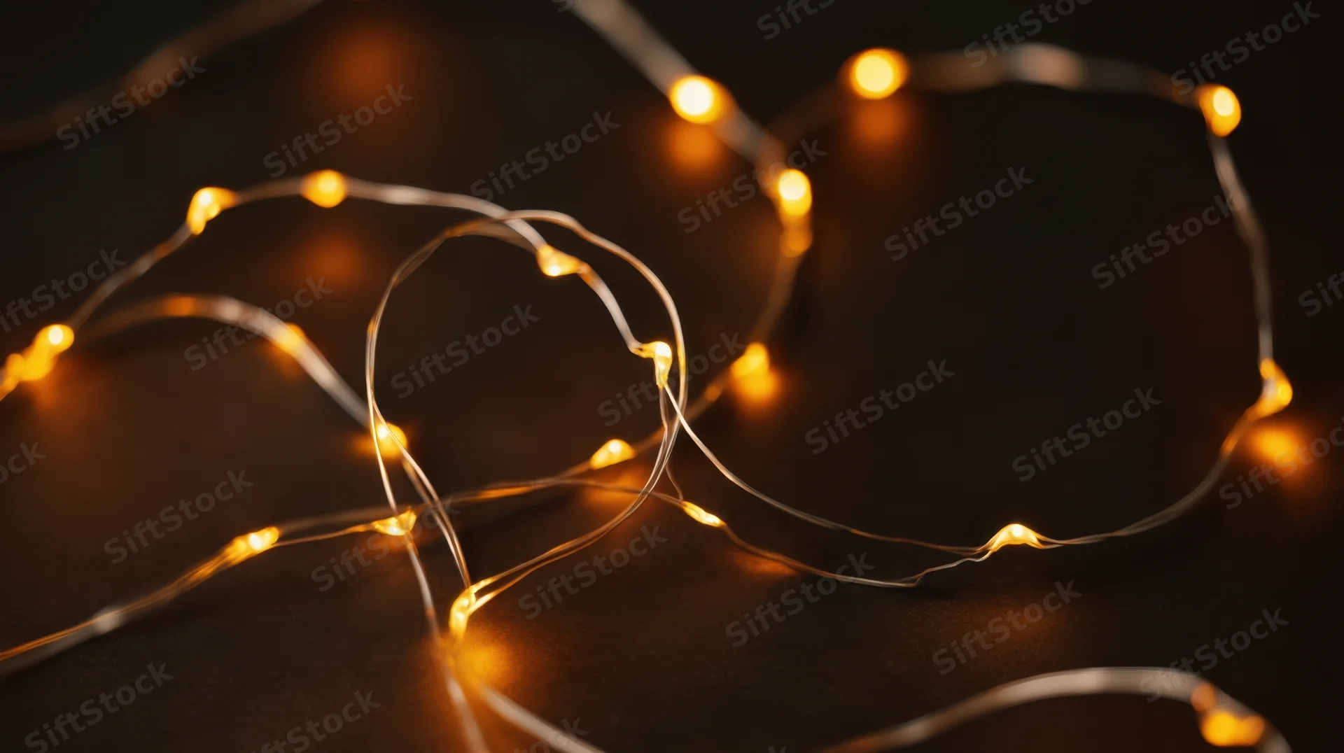 Tangled string of warm glowing fairy lights on dark surface