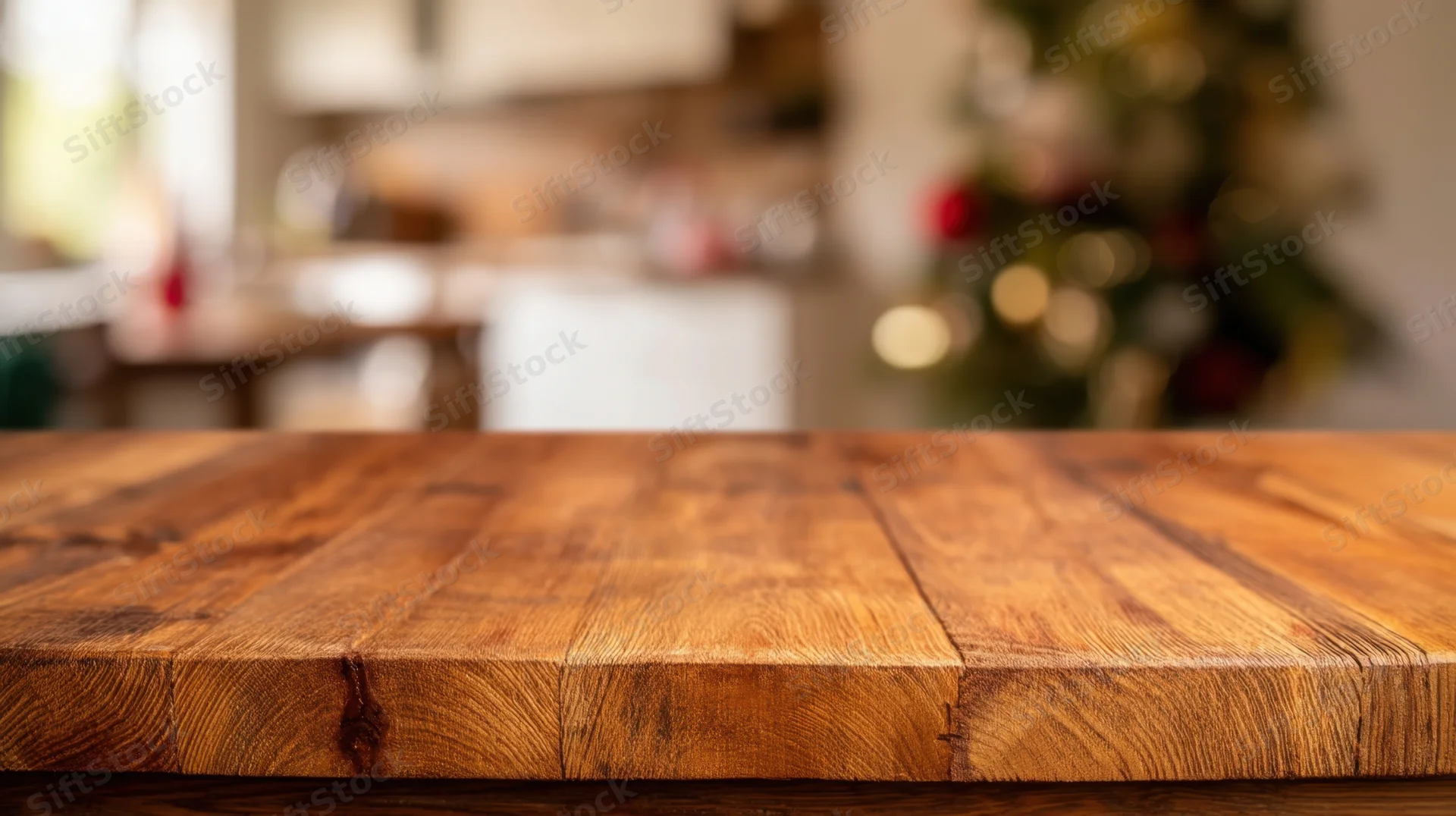 Wooden table surface in a kitchen with blurred christmas tree in background