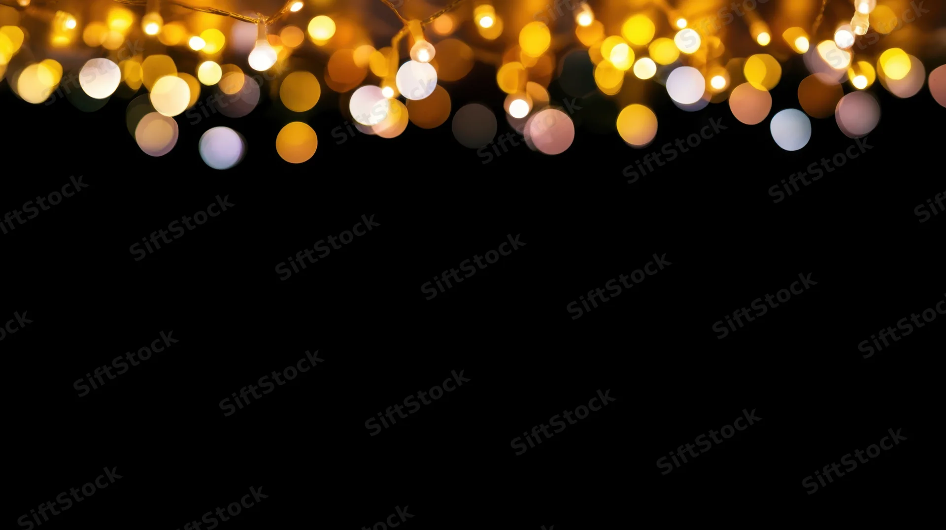 Decorative string lights glowing softly across the top of a black background with bokeh effect and copyspace below