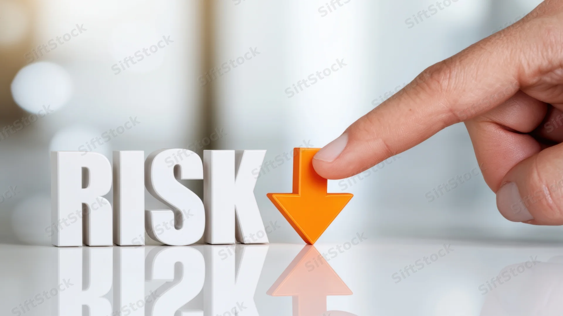 Finger pressing down arrow next to 3d risk letters on reflective surface