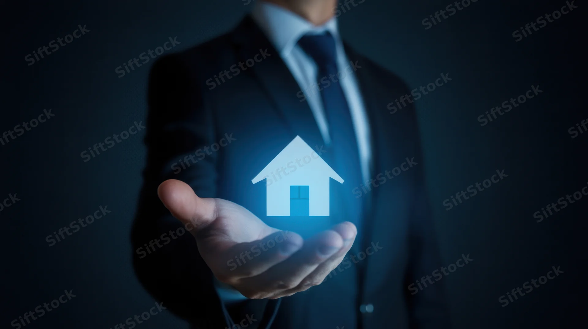 Businessman holding glowing digital house icon in palm against dark background