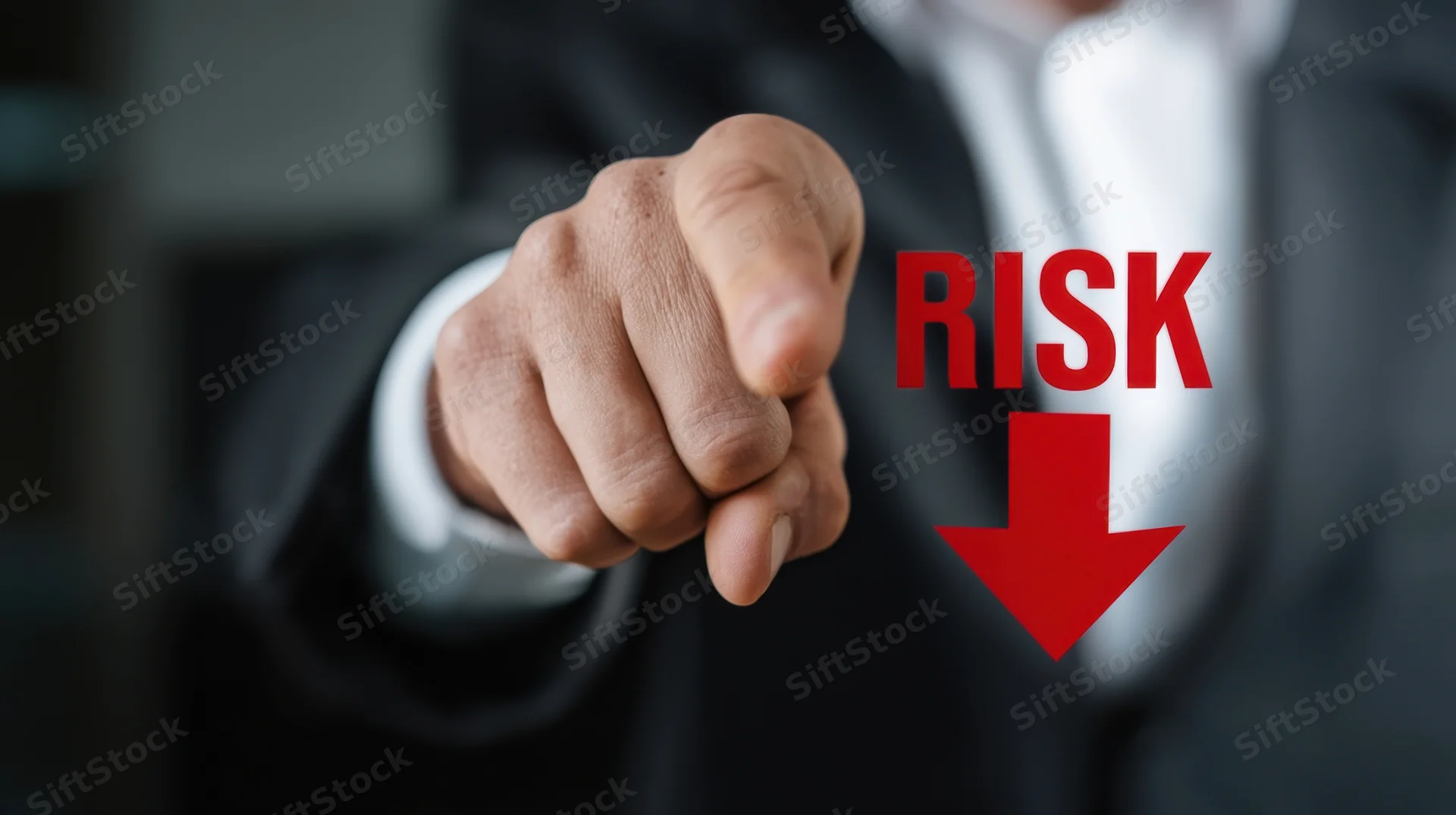 Man in suit pointing at red risk down arrow on digital screen