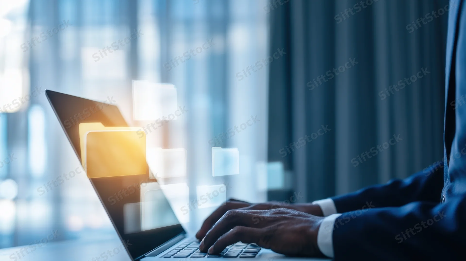Man in suit typing on laptop with digital files floating above screen in office setting