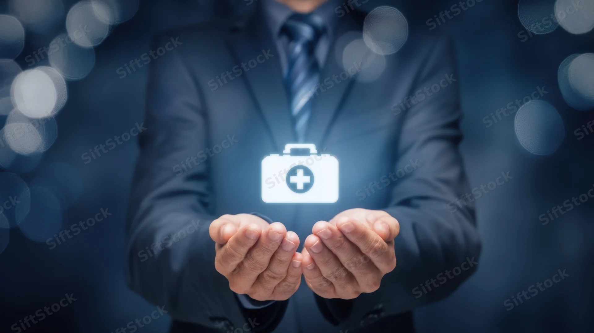 Man in suit holding glowing medical briefcase icon in hands against dark bokeh background