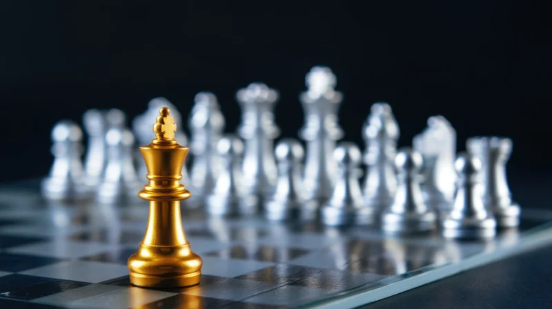 Golden chess king standing on board facing silver pieces in strategic formation
