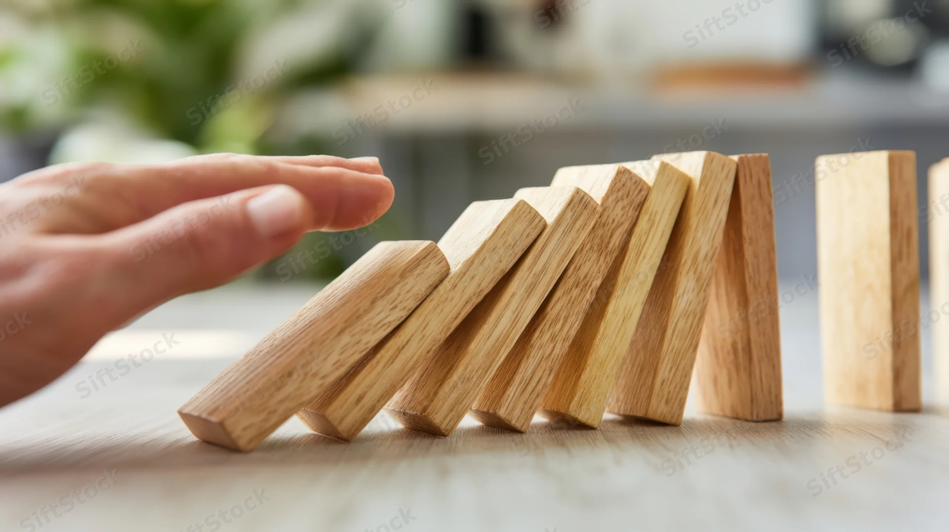 Hand stopping falling wooden blocks on a desk