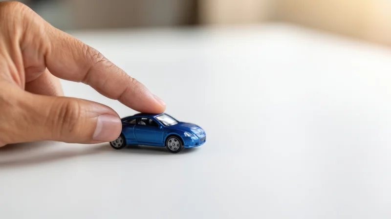 Hand touching blue toy car on white surface