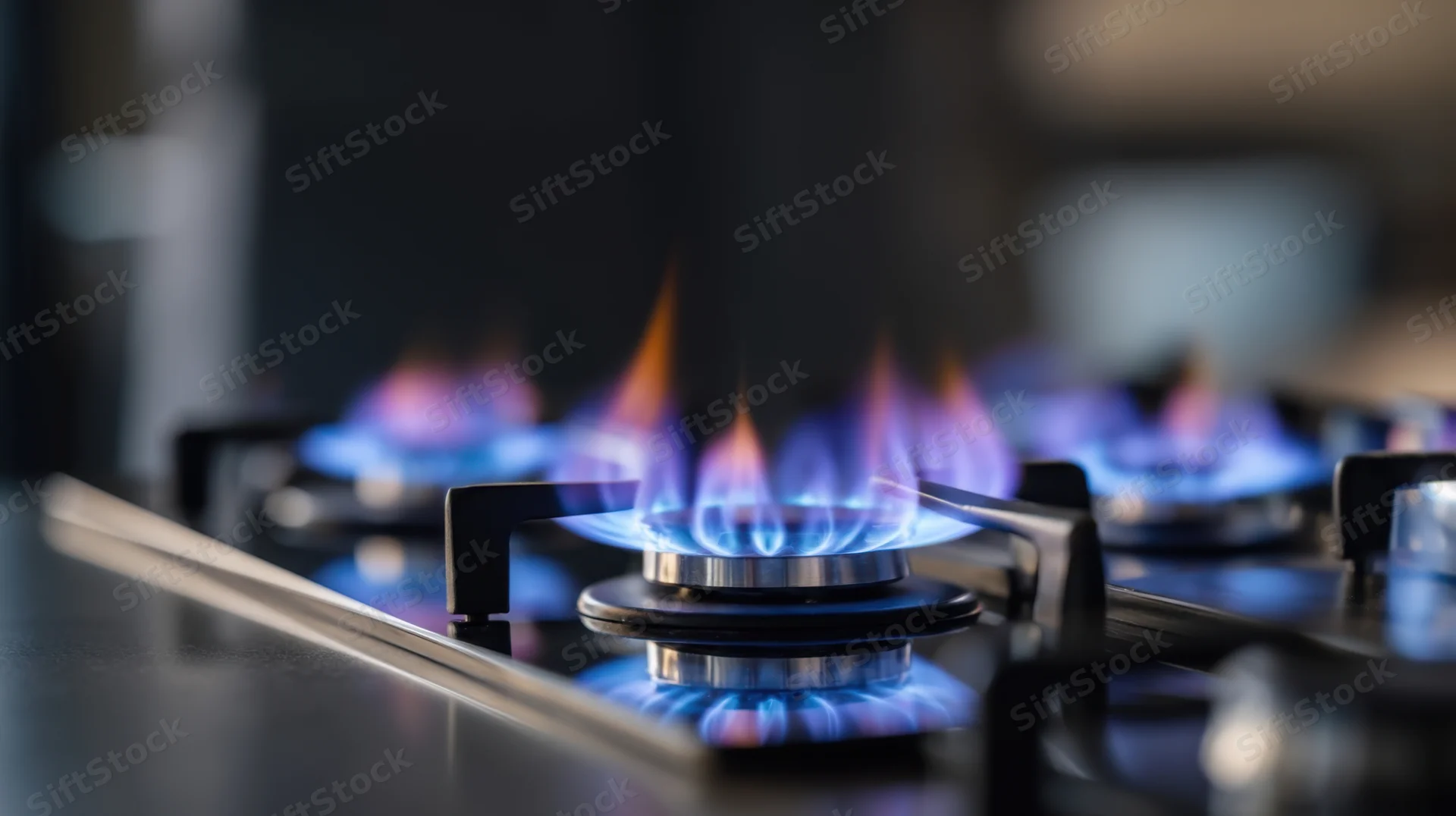 Close-up of blue flames burning on a gas stove cooktop in a kitchen