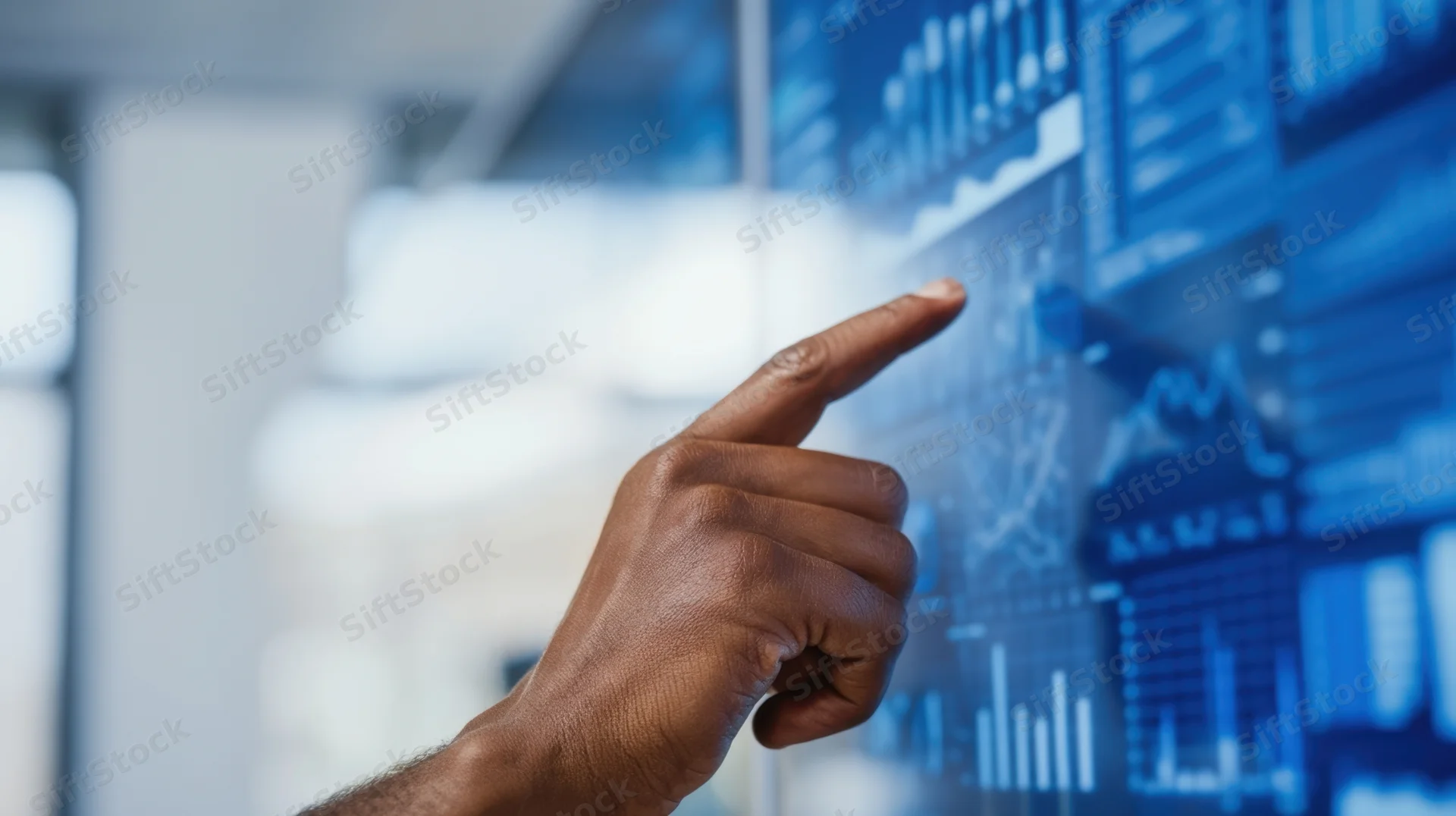 Hand pointing at digital data display in office setting
