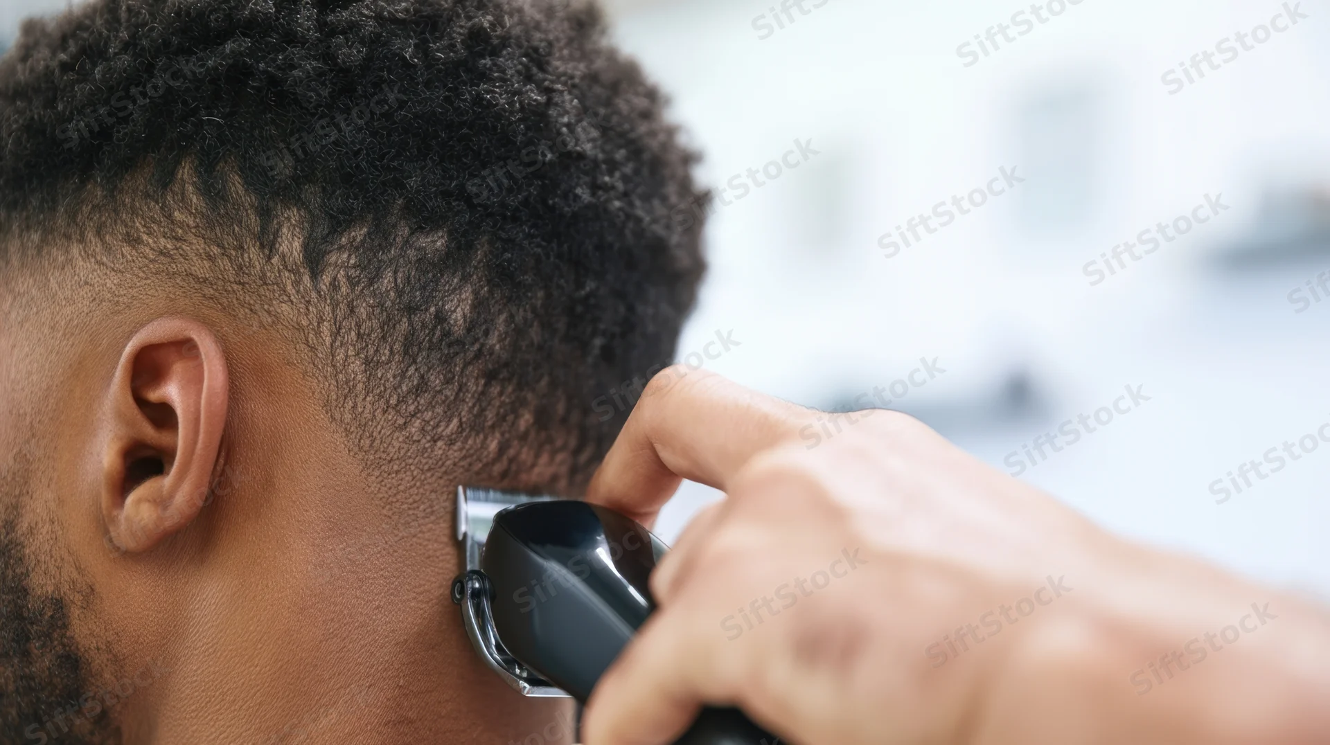 Barber trimming a man's hair with an electric clipper at a salon