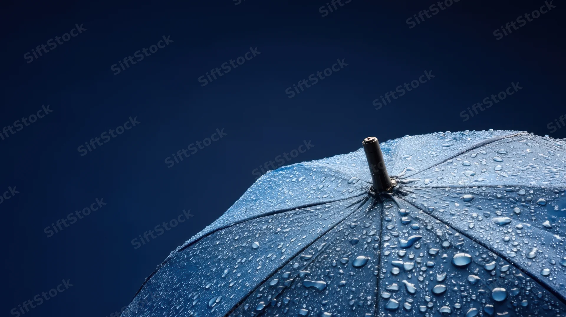 Close-up of a blue umbrella covered in raindrops against a dark sky