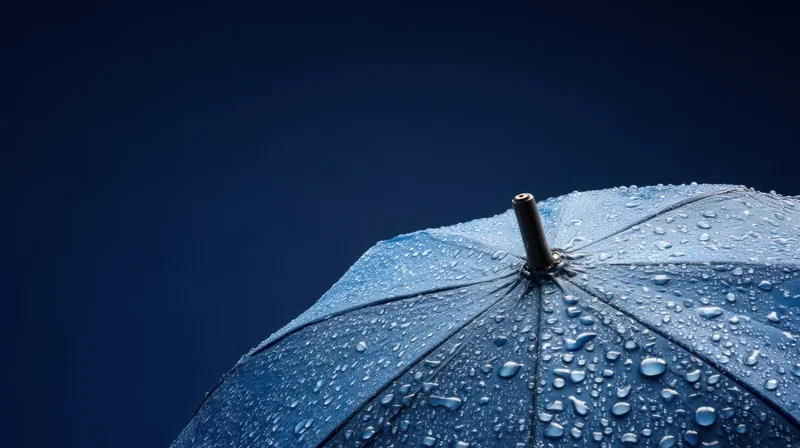 Close-up of a blue umbrella covered in raindrops against a dark sky