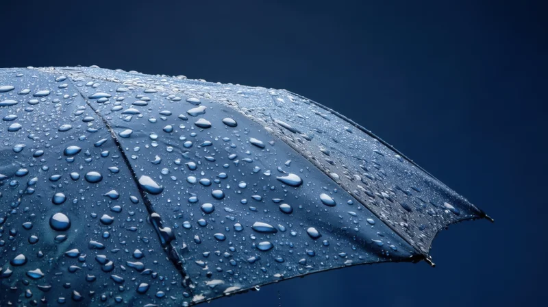 Close-up of a blue umbrella covered in raindrops against a dark sky