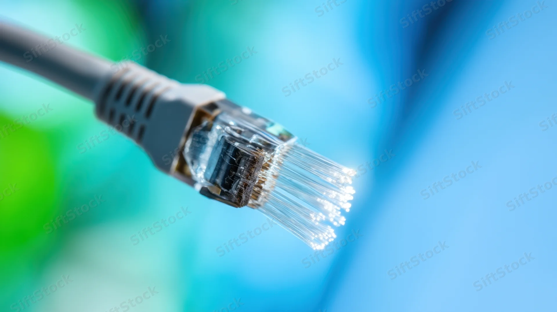 Close-up of an ethernet cable connector with exposed fiber optic strands against a blurred blue and green background