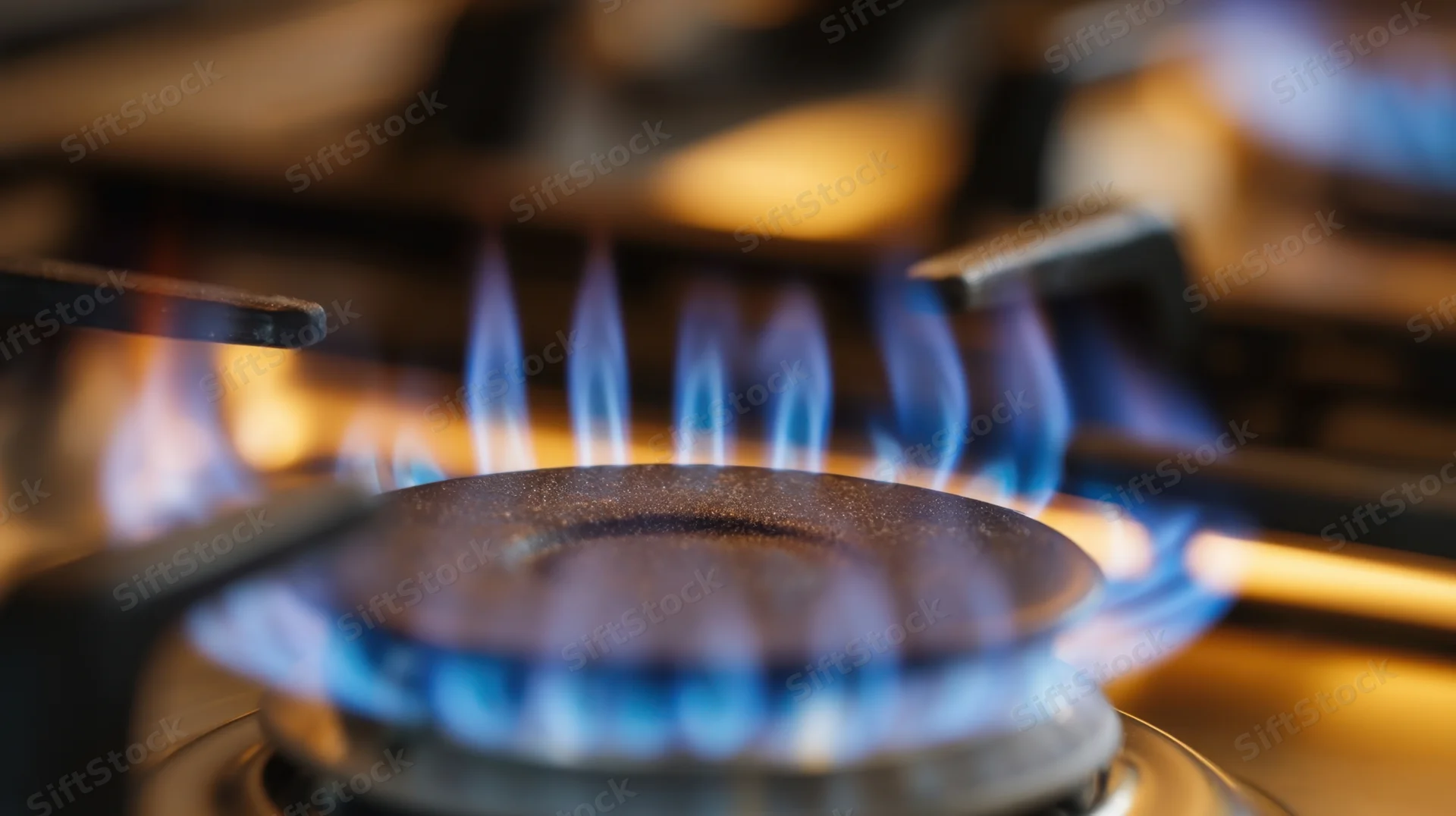 Close-up of blue flames burning on a gas stove burner in a kitchen