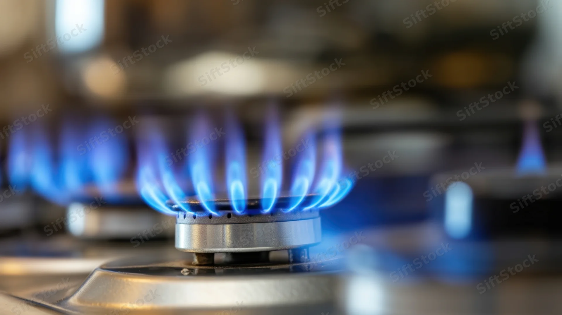 Close-up of blue flames on a gas stove burner in a kitchen
