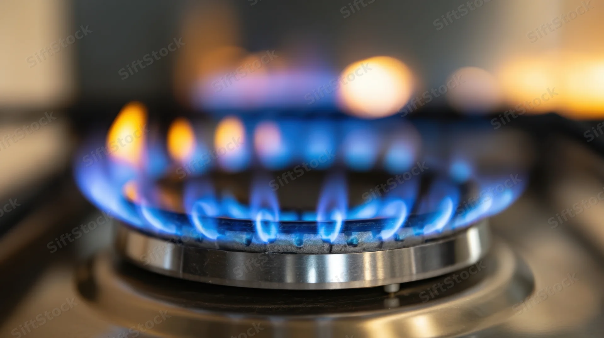 Close-up of blue flames burning on a gas stove burner in a kitchen